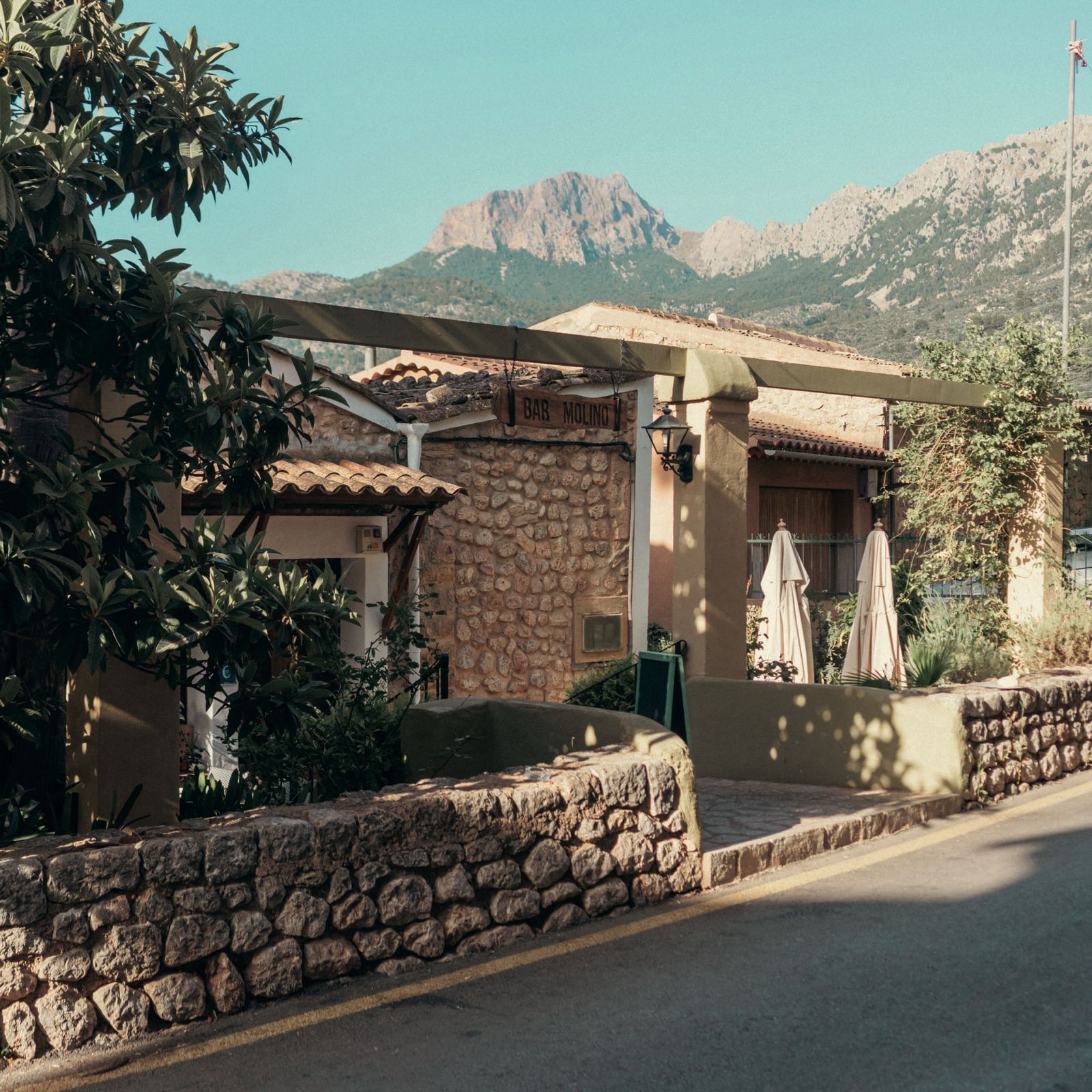 Außenansicht des Bar Molino in Sóller, ein Steinhaus vor den Bergen der Tramuntana