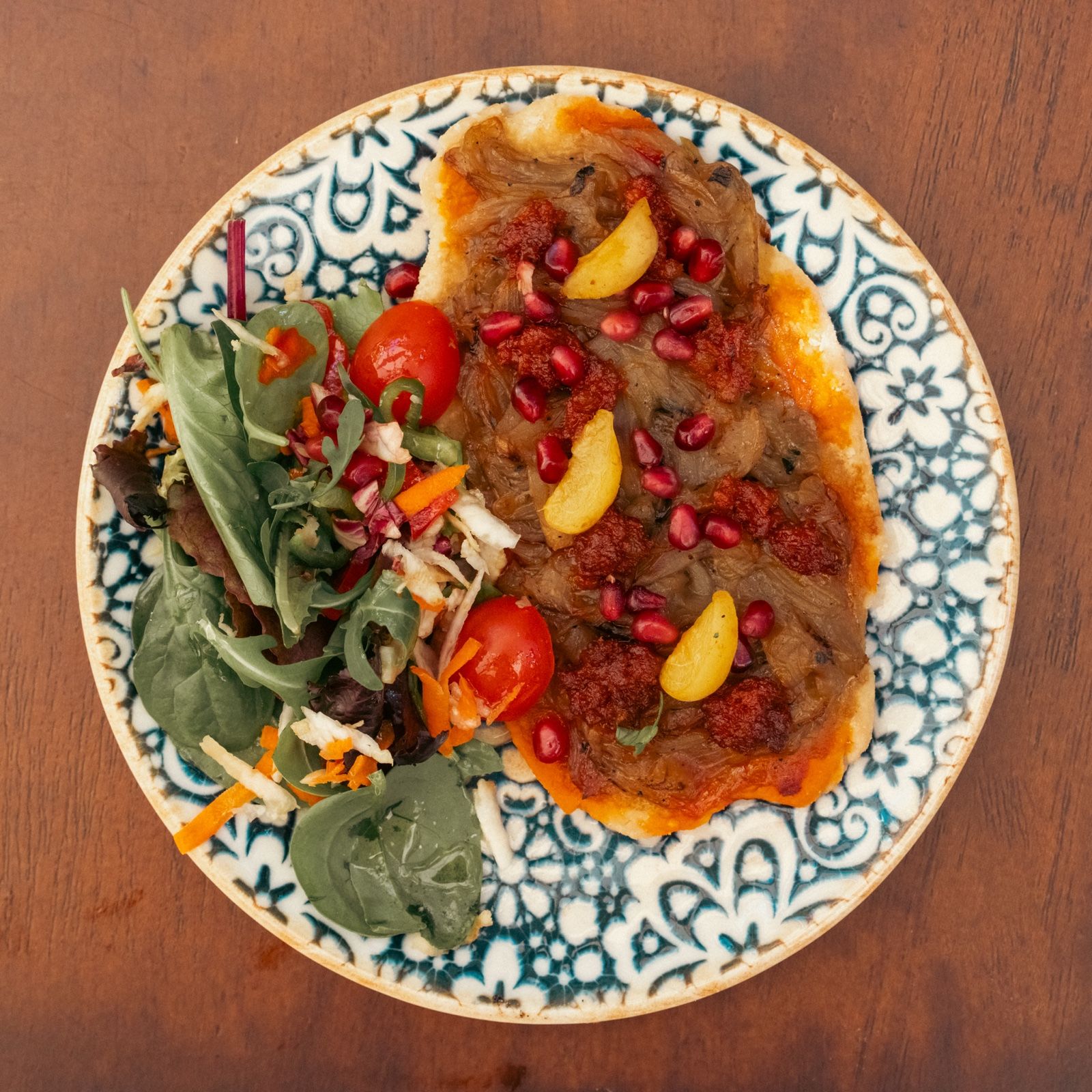 Coca de xeixa mit Sobrasada, Zwiebeln und Granatapfelkernen, mit Salat