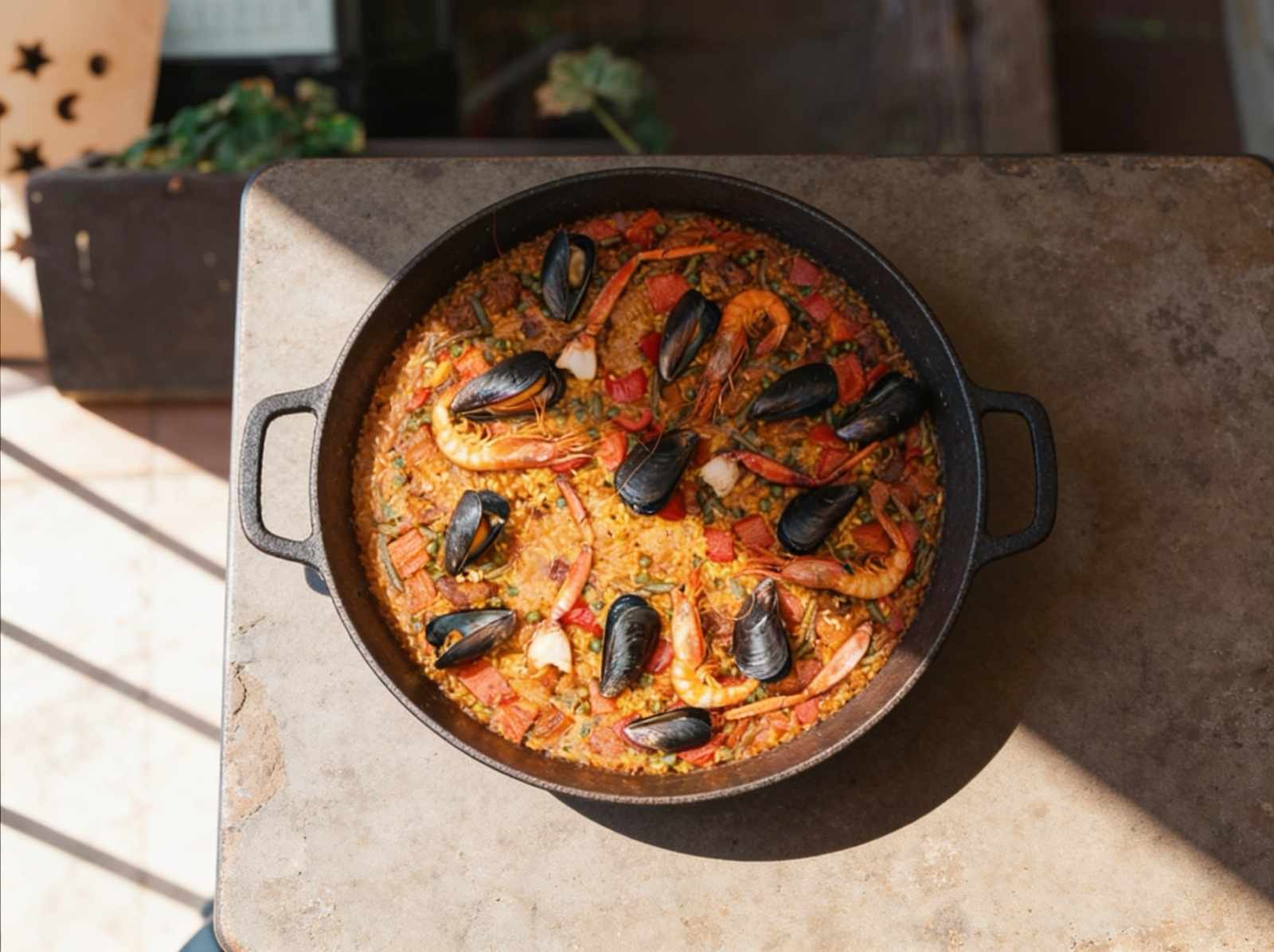 Paella con sepia, cerdo, pollo, recién hecha, acompañada con gambas, cangrejo y mejillones en la terraza del Bar Molino, Sóller