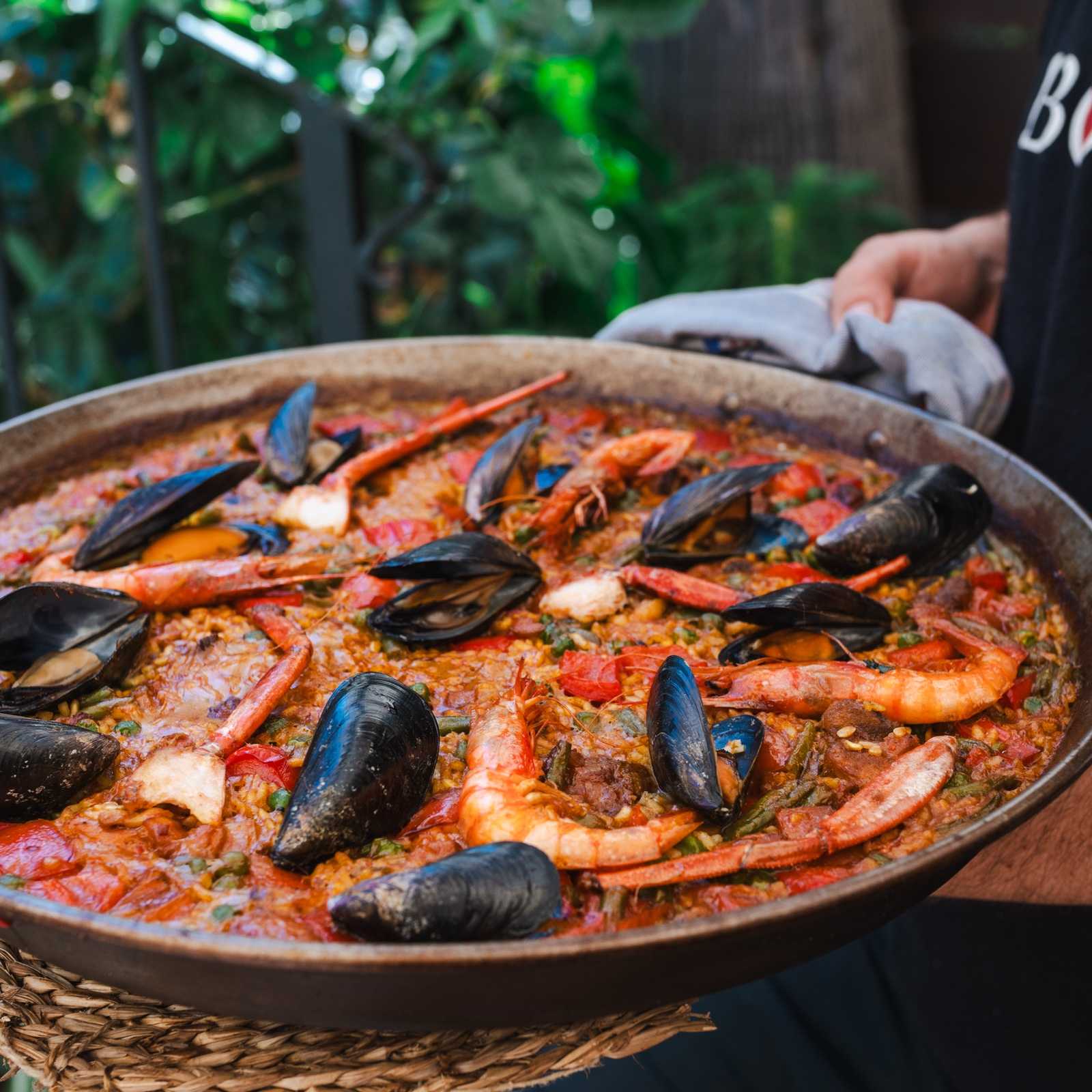 Gemischte Paella vom Bar Molino mit Schwein, Hühnchen, Garnelen, Muscheln, Krebsscheren, Reis und roter Paprika, bereit zum Teilen