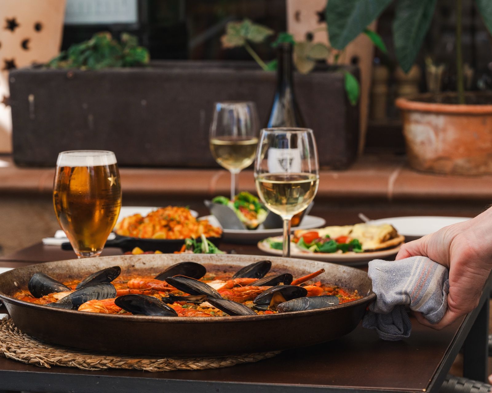 Paella mixta recién hecha lista para servir, sostenida sobre la mesa de la terraza
