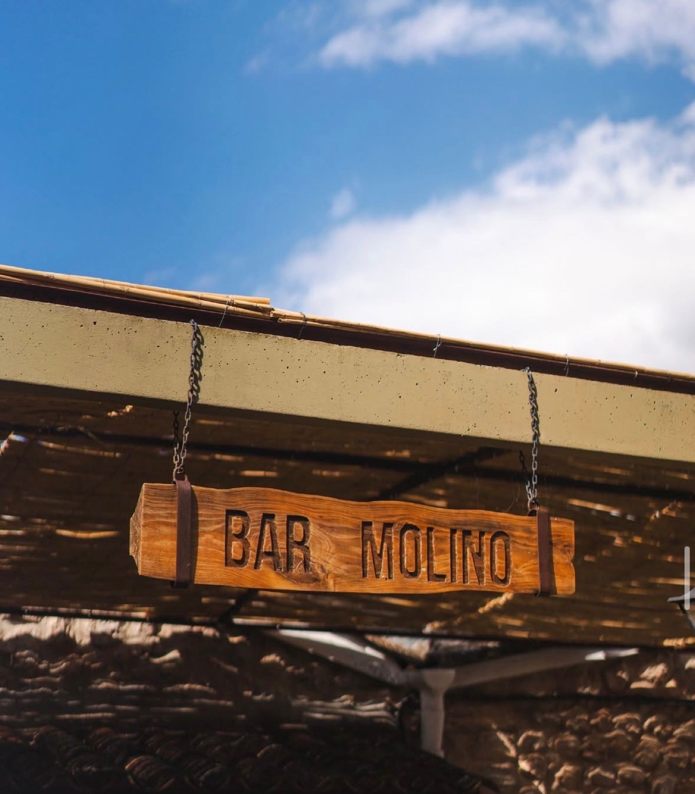 Handgeschnitztes Holzschild «Bar Molino» unter dem Schilfrohr-Terrassendach