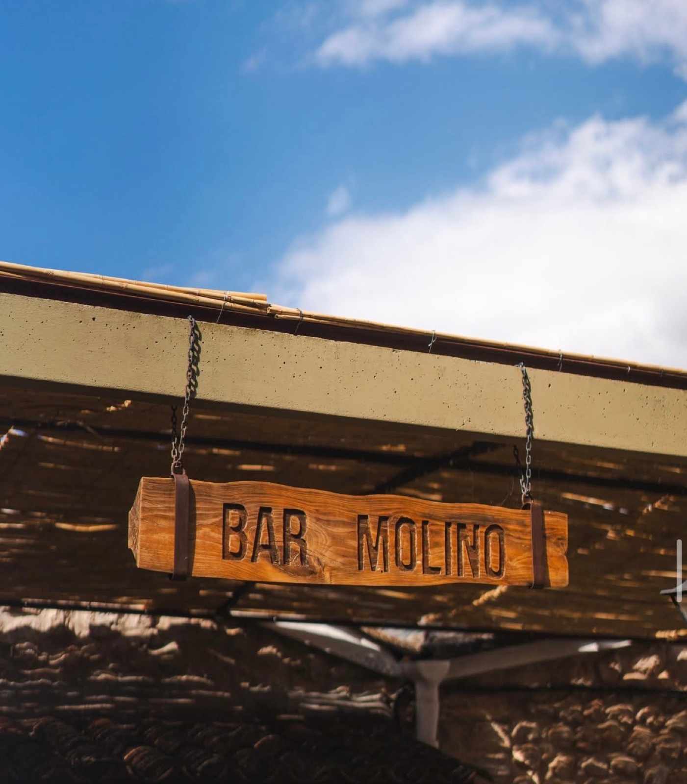 Handgeschnitztes Holzschild «Bar Molino» unter dem Schilfrohr-Terrassendach