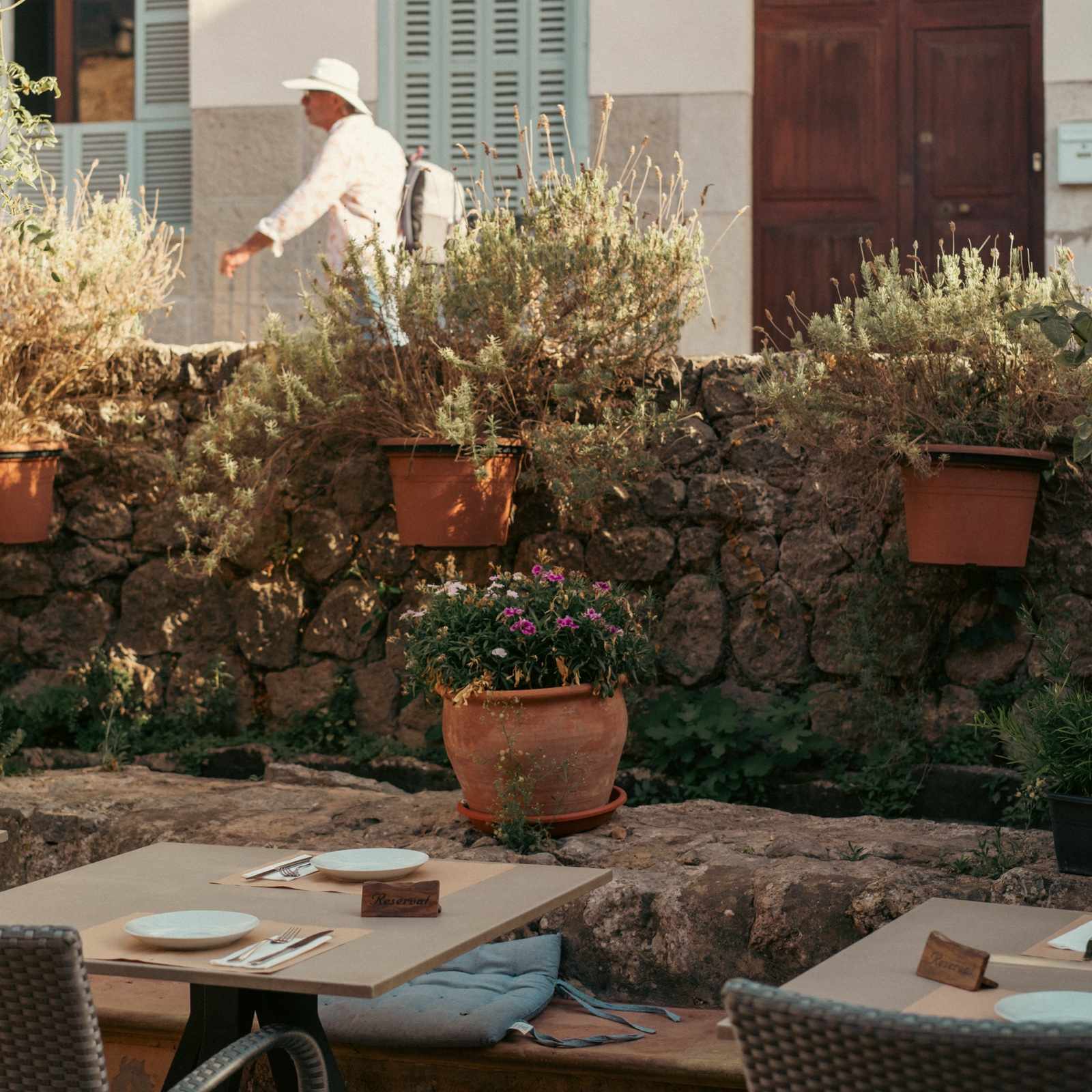 Terrasse des Bar Molino neben einer Steinmauer mit Lavendeltöpfen und gedeckten Tischen in Sóller